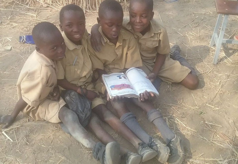 Picture of four boys sharin one book